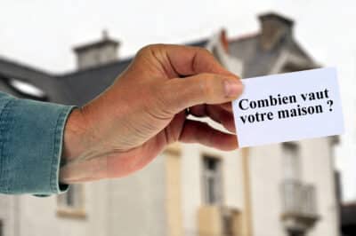 Homme tenant une carte avec combien vaut votre maison écrit dessus