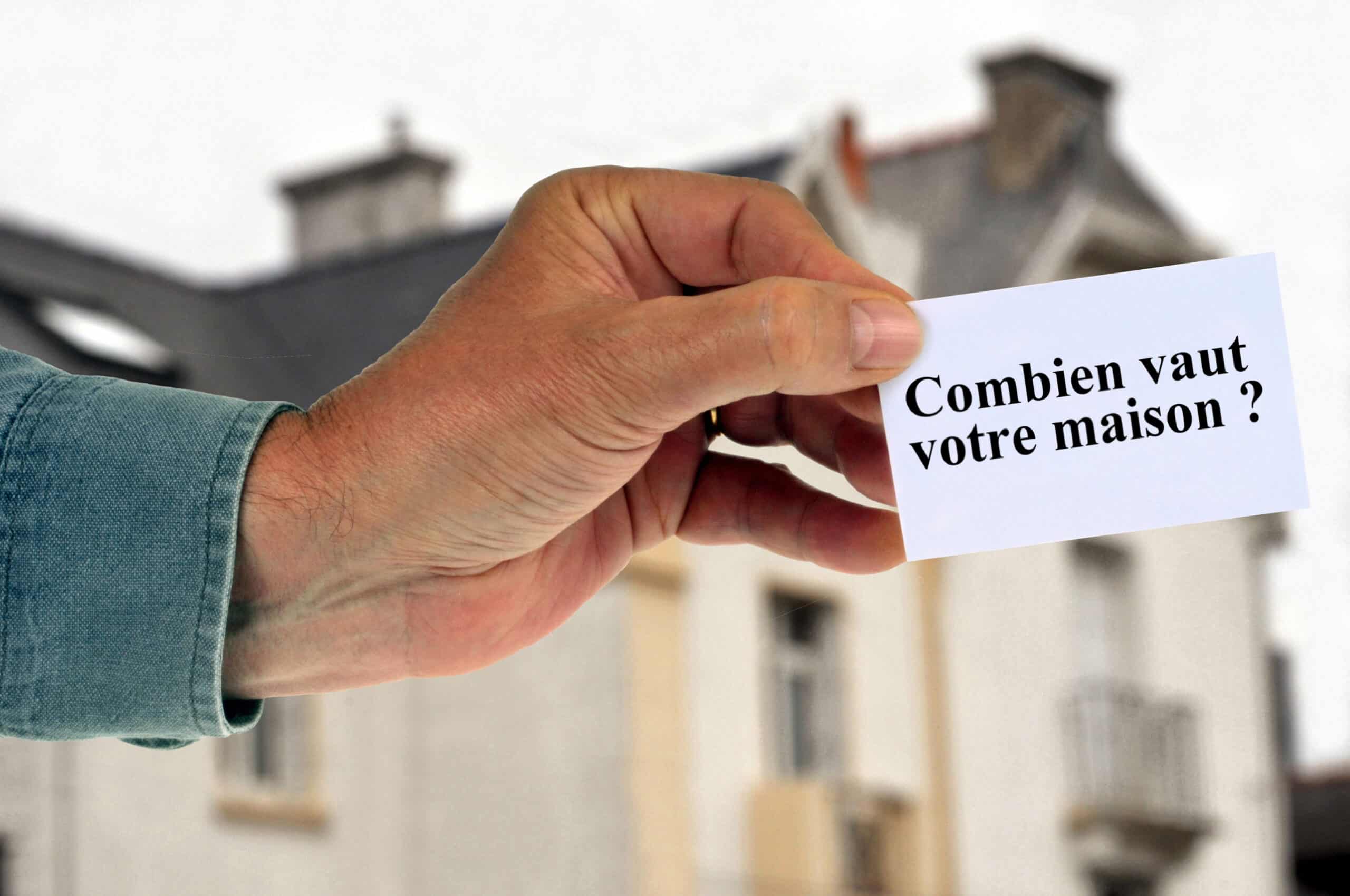 Homme tenant une carte avec combien vaut votre maison écrit dessus